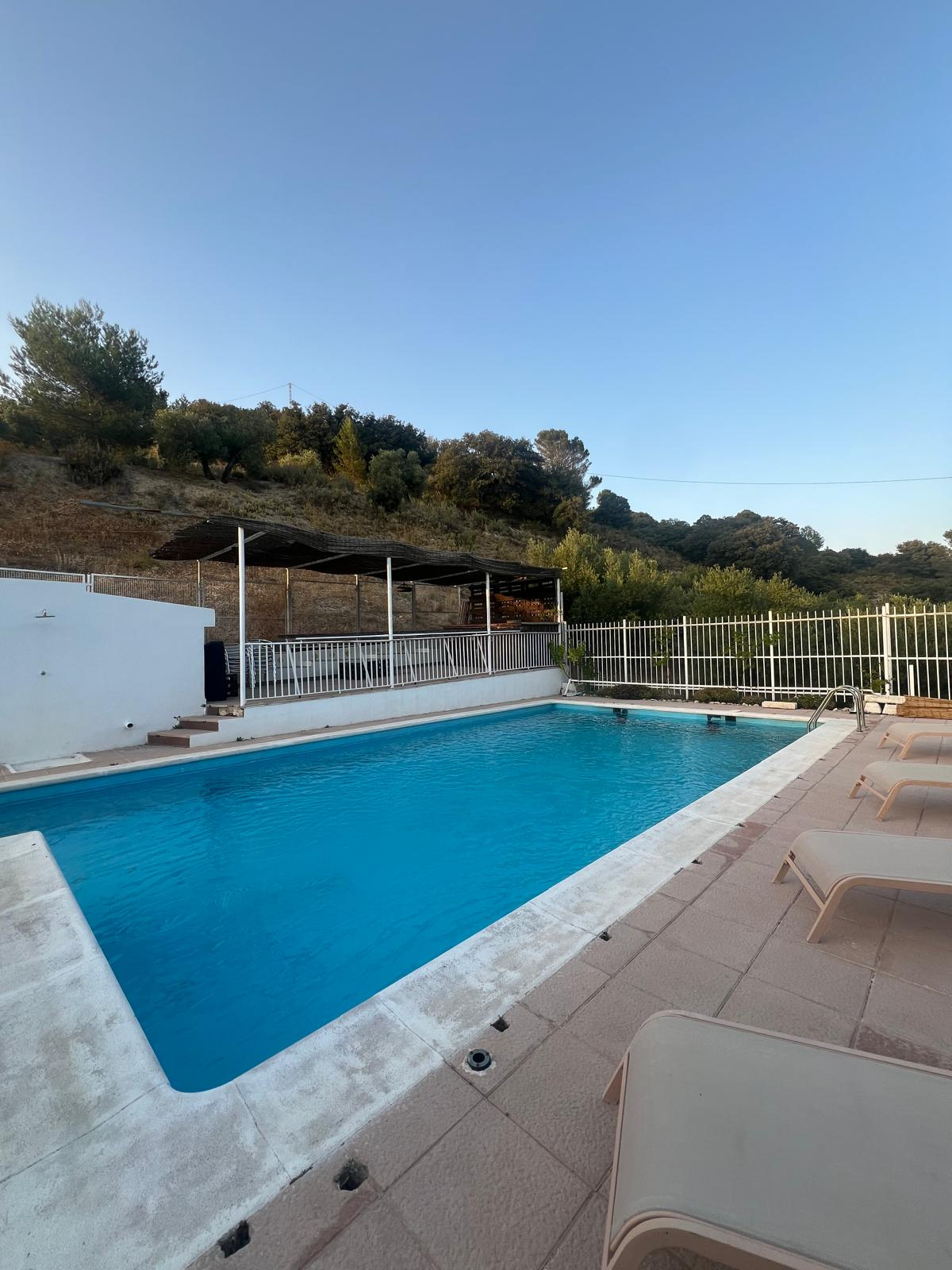 Piscina de Villa de Dulce al atardecer, con hamacas y pérgola frente a la sierra de Jaén