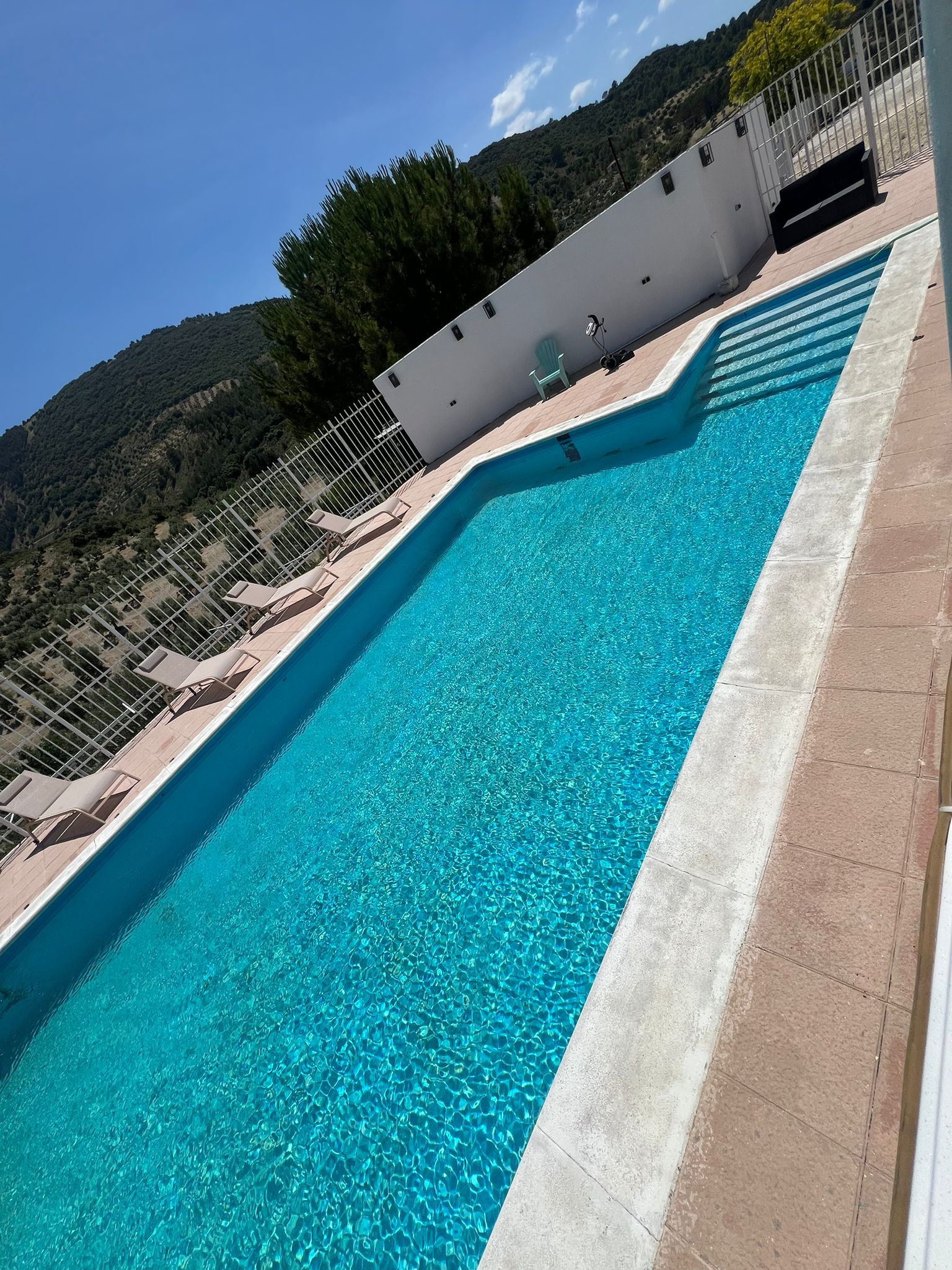 Piscina con agua cristalina y tumbonas bajo el sol