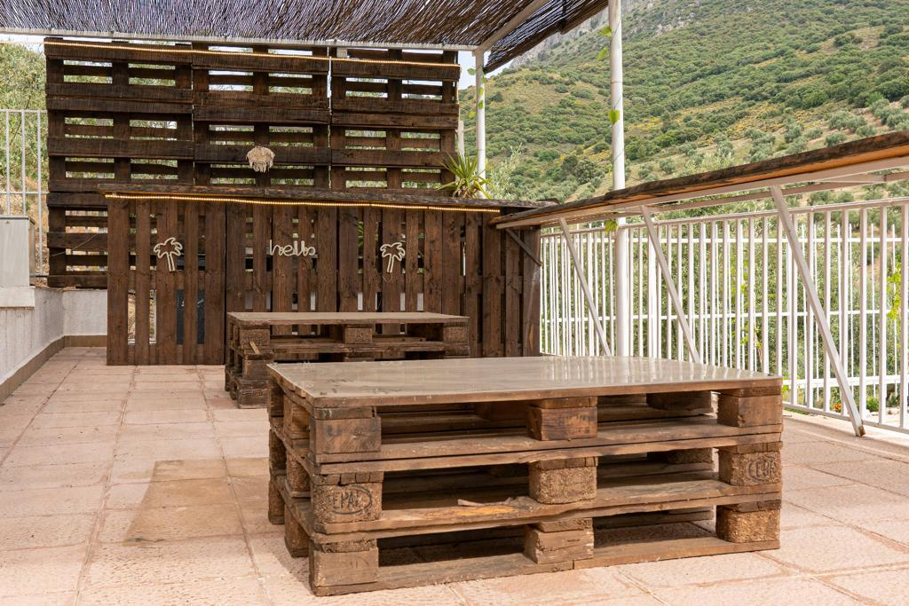 Terraza exterior con mesas de palés y vistas al campo